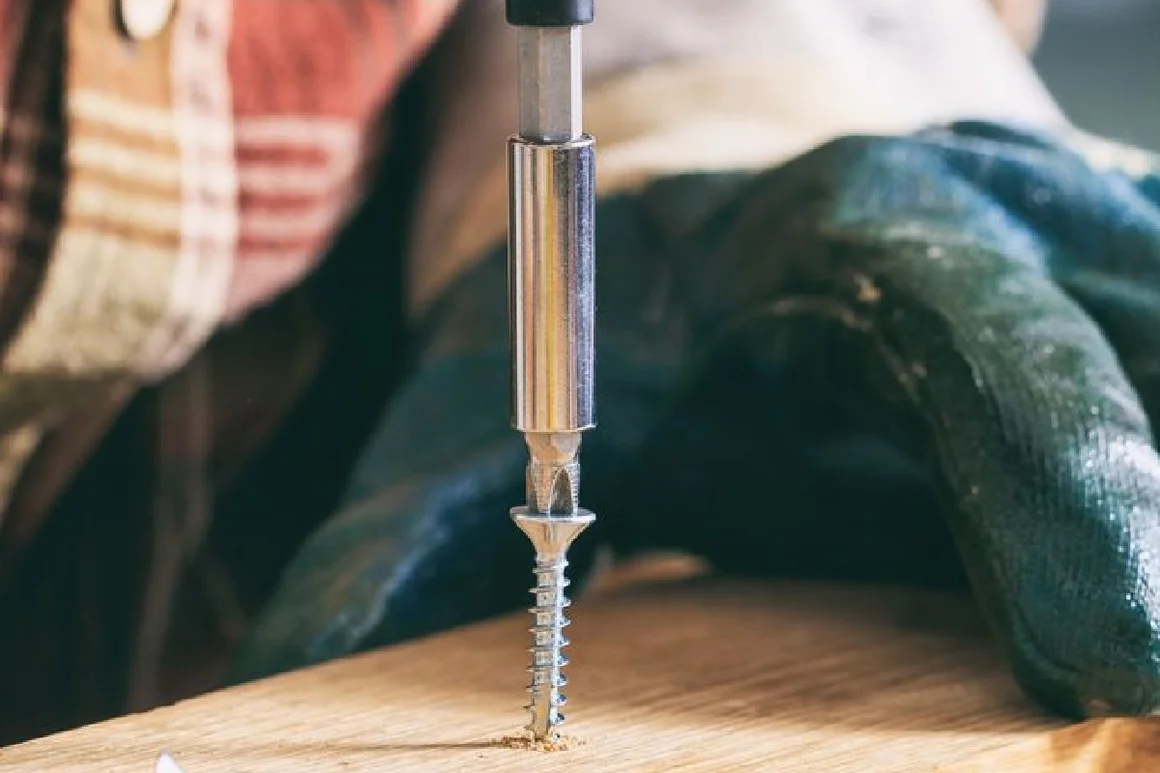 Schraubendreher dreht Schraube ins Holz